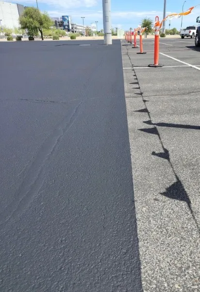 Before and after commercial sealcoating showing faded gray asphalt next to fresh black sealer in Charlotte NC